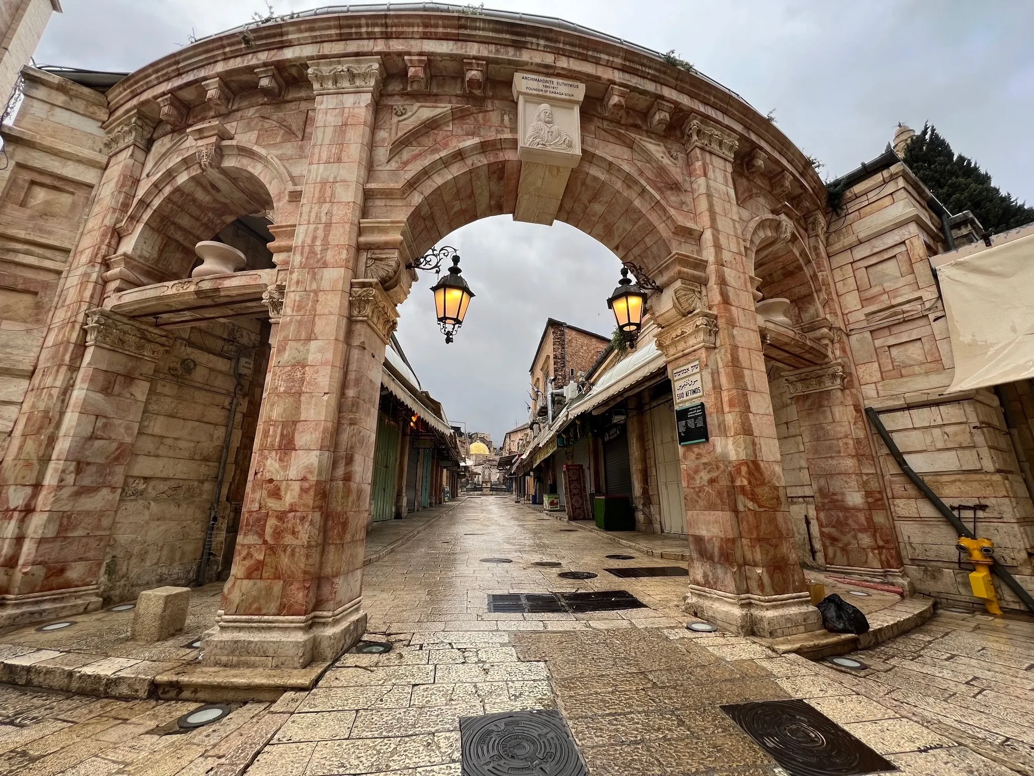 A carved stone archway over a quiet market lane in Jerusalem's Old City