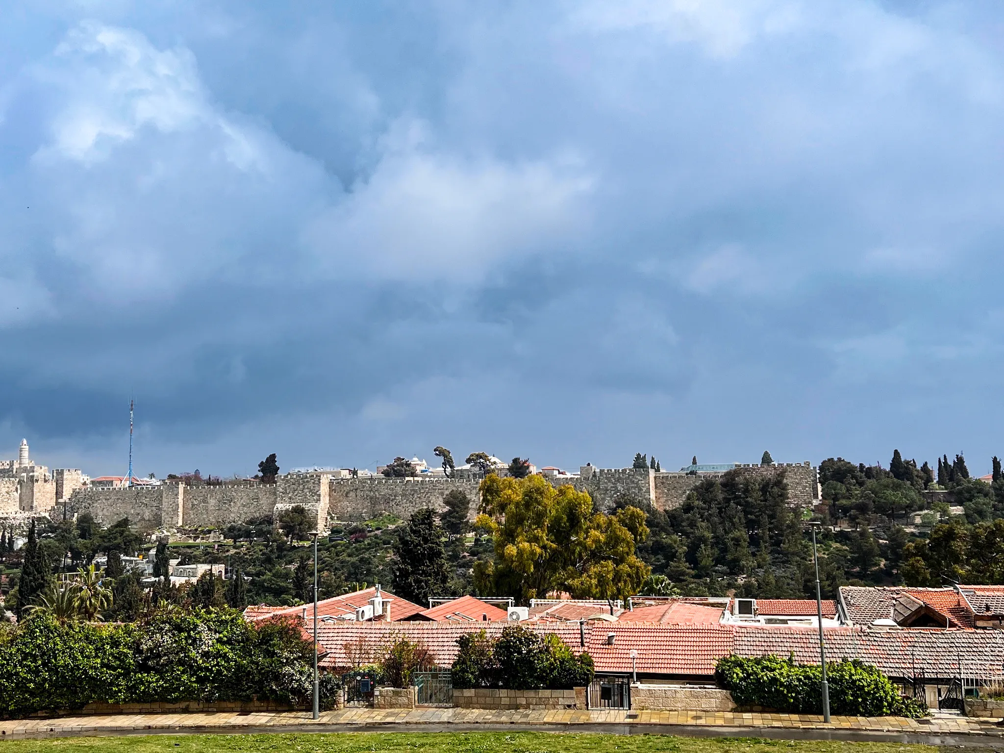 Jerusalem's Old City walls seen across red-roofed houses under a wide sky